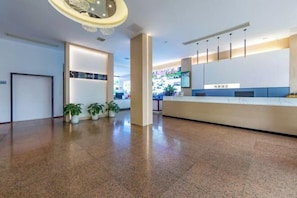 Een moderne receptiezone met een receptiebalie, potplanten en een schone, gepolijste vloer.