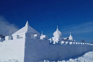 Un bâtiment enneigé, doté de structures en forme de dôme, entouré d’un mur également recouvert de neige.