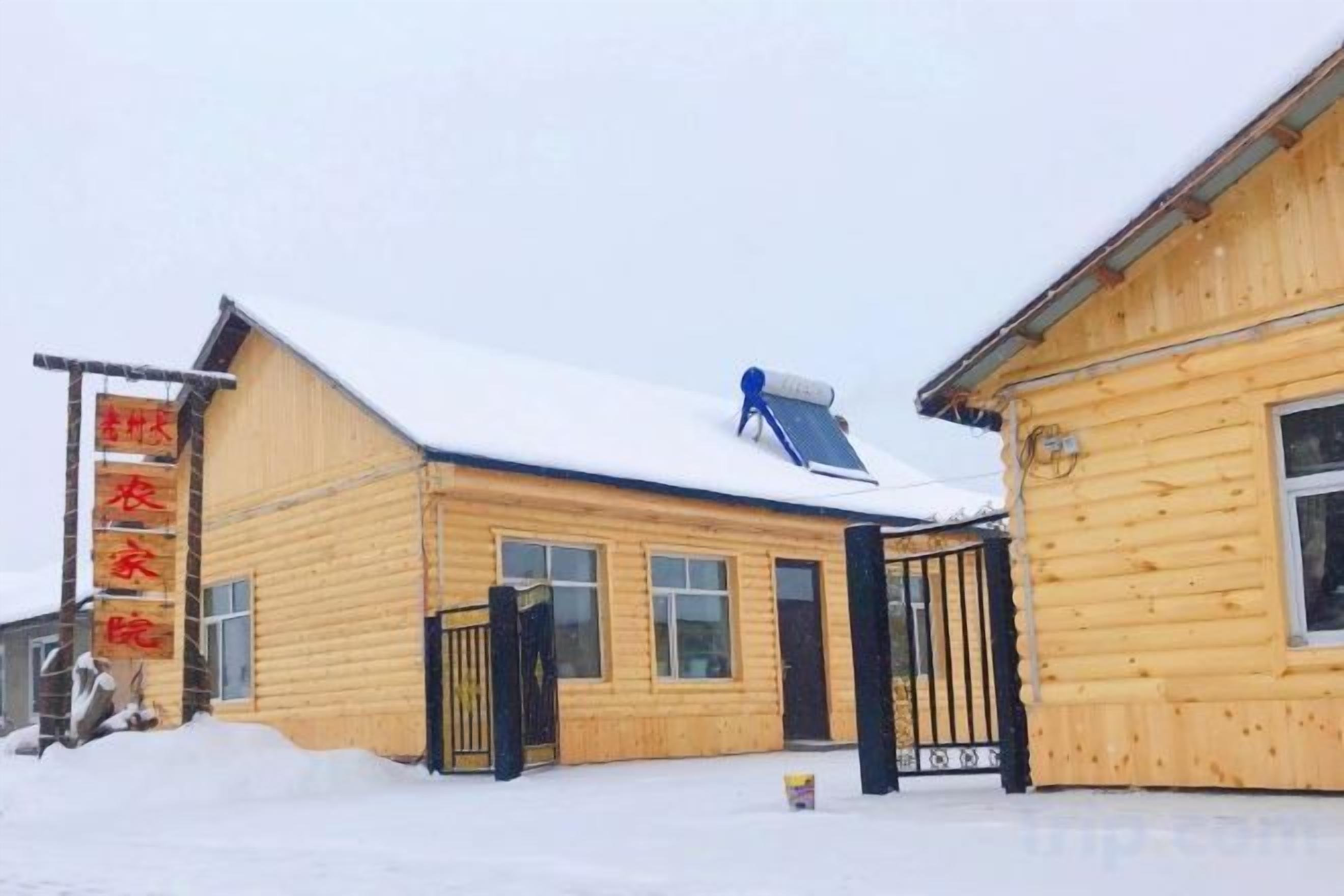 A wooden building with a snow-covered roof and a blue solar panel.