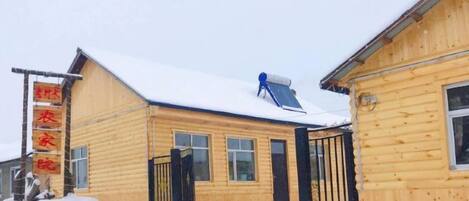 Un edificio de madera con techo nevado y un panel solar azul.