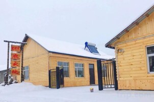 Un edificio de madera con techo nevado y un panel solar azul.