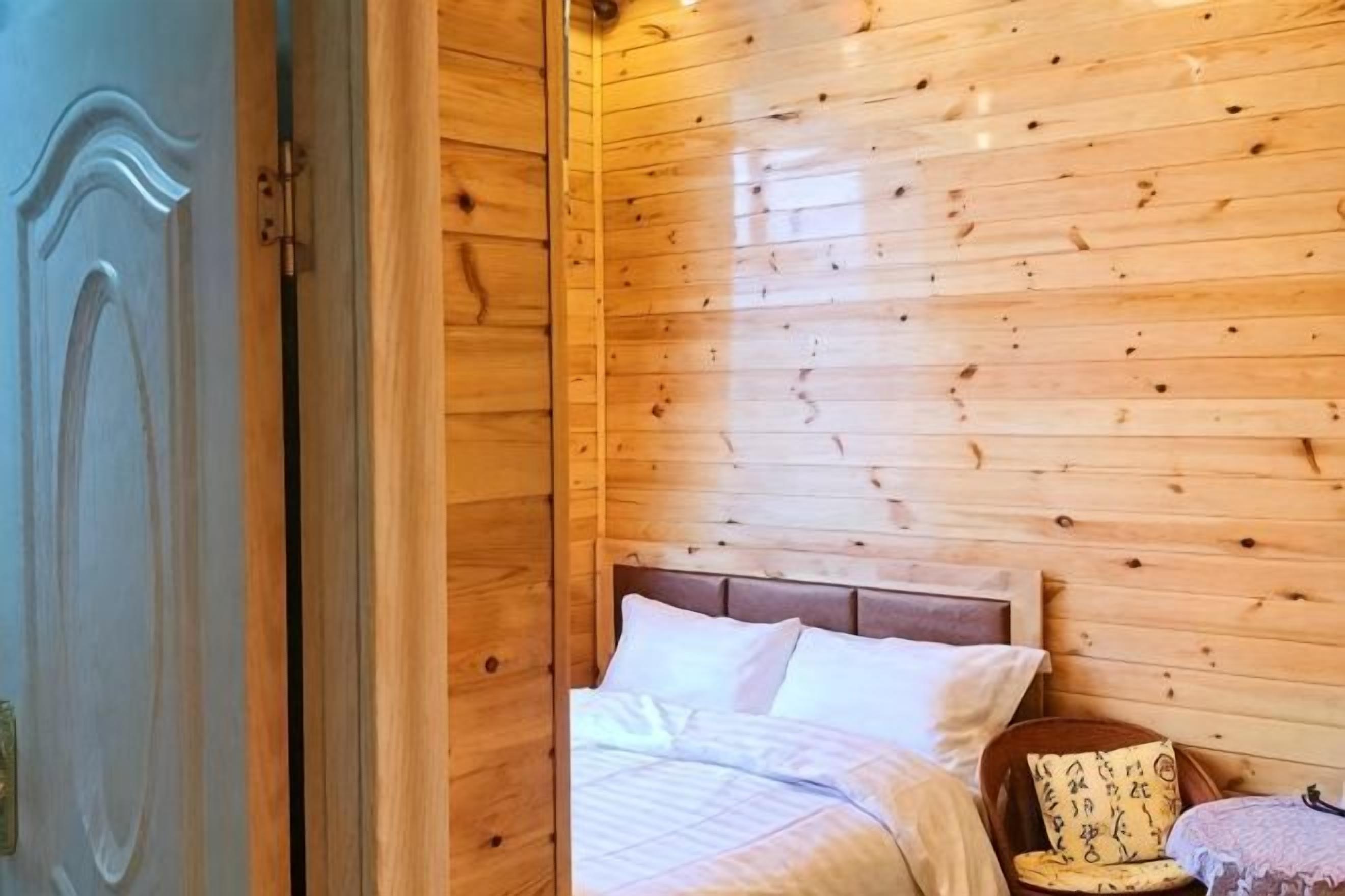 Una habitación con paneles de madera, una cama, una silla y una pequeña mesa.