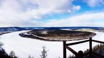 A panoramic view of a snow-covered landscape with a wooden deck and railing.