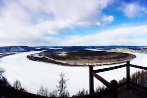 Vista panorámica de un paisaje nevado con una terraza y barandilla de madera.