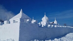 A snow-covered building with domed structures, a clear sky, and a snow-covered ground.
