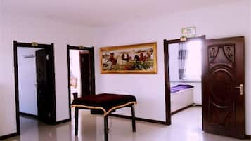 A room with a bench, a door, and a painting on the wall.