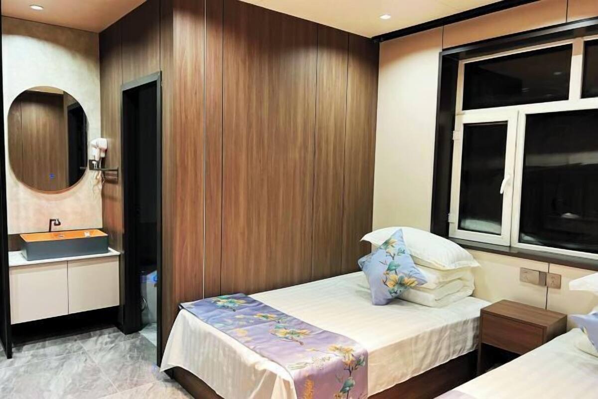 Ein Hotelzimmer mit einem Bett, einem Nachttisch, einem Spiegel, einem Fenster und einer Wand mit Holzverkleidung.