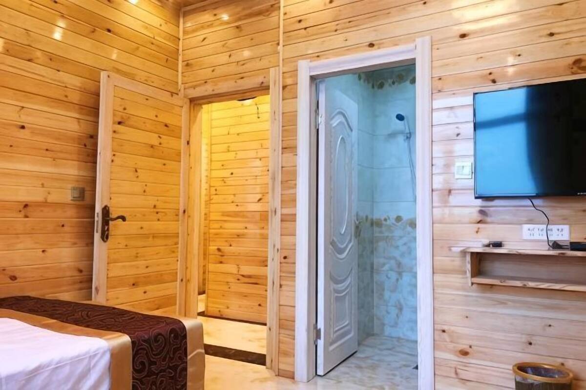 Ein Zimmer mit Holzvertäfelung, einem Bett, einem Fernseher und einer Duschkabine.