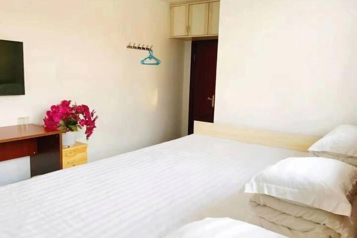 Ein Hotelzimmer mit einem Bett, einem Holztisch, einem Fernseher, einem Kleiderschrank und einem Wandhaken.