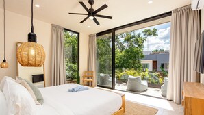 Une chambre moderne avec un grand lit, un ventilateur de plafond et une vue sur l’extérieur.