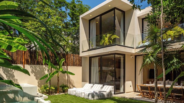 Une maison moderne à deux étages, dotée d’une piscine, d’un espace de détente extérieur et d’une végétation luxuriante.