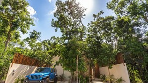 Un VUS bleu est garé dans une allée bordée d’une clôture en bois et d’arbres.