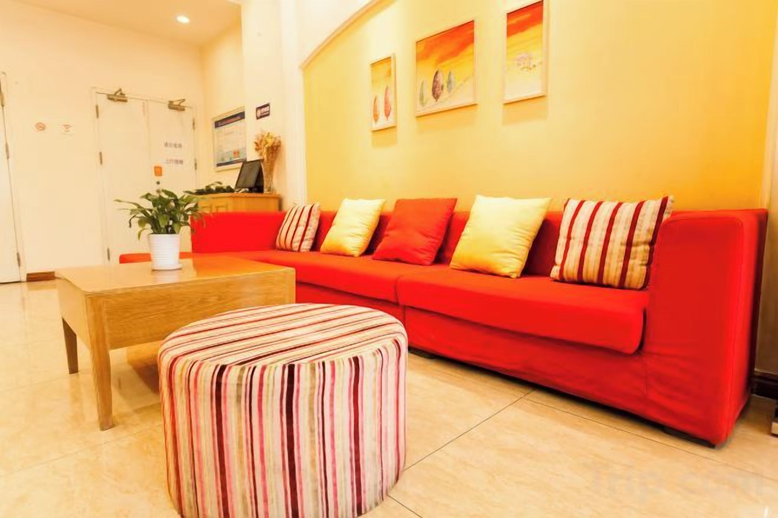A modern living room with a red sofa, a wooden coffee table, and a striped ottoman.