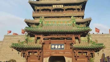 A traditional multi-tiered gate with intricate wooden carvings and a sign in the center.