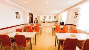 A dining area with multiple tables and chairs, a kitchen in the background, and artwork on the walls. - Home Inn (Taiyuan Jinci Road Jinyang Lake Park) (Taiyuan)