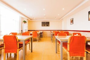 A dining area with multiple tables and chairs, a kitchen area, and a tiled floor. - Home Inn (Taiyuan Jinci Road Jinyang Lake Park) (Taiyuan)