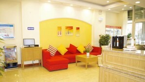 A reception area with a red sofa, a wooden coffee table, and a counter with a refrigerator. - Home Inn (Taiyuan Jinci Road Jinyang Lake Park) (Taiyuan)