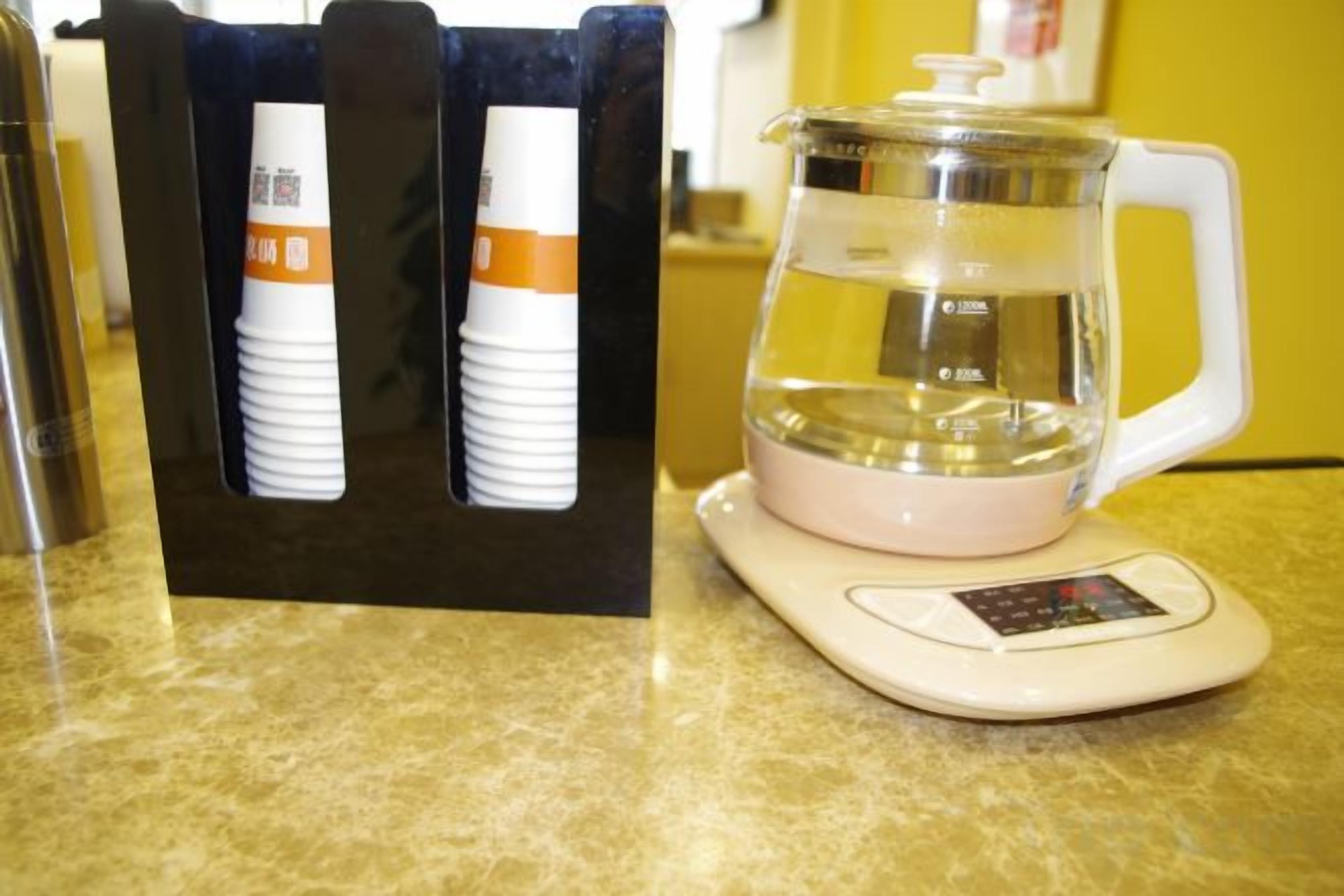 Una encimera de cocina con una cafetera, una balanza y un recipiente de vidrio.