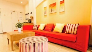A modern living room with a red sofa, striped ottoman, and a wooden coffee table. - Home Inn (Taiyuan Jinci Road Jinyang Lake Park) (Taiyuan)