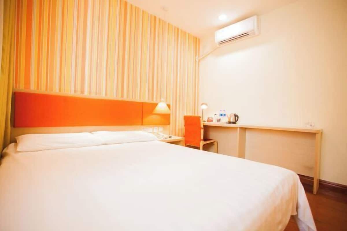 Habitació d'hotel amb llit, escriptori, làmpada i aire condicionat.
