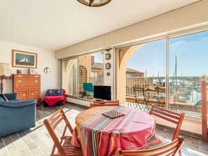 A spacious balcony with a dining table, chairs, and a TV.