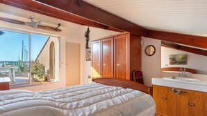 Une chambre avec un grand lit, une armoire en bois et une salle de bain équipée d’un lavabo et d’un miroir.