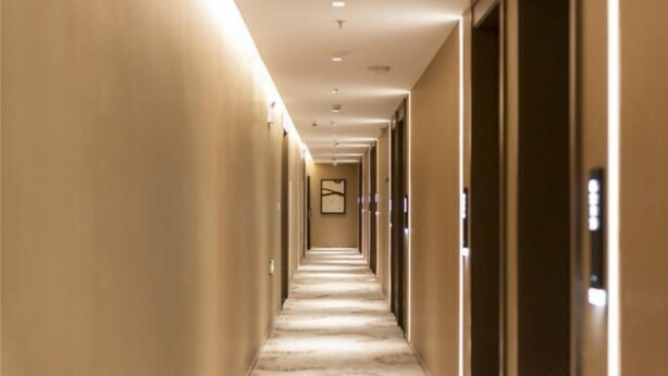 A long, narrow hotel corridor with a carpeted floor and doors on both sides. - Joyous Hotel (Shanghai)