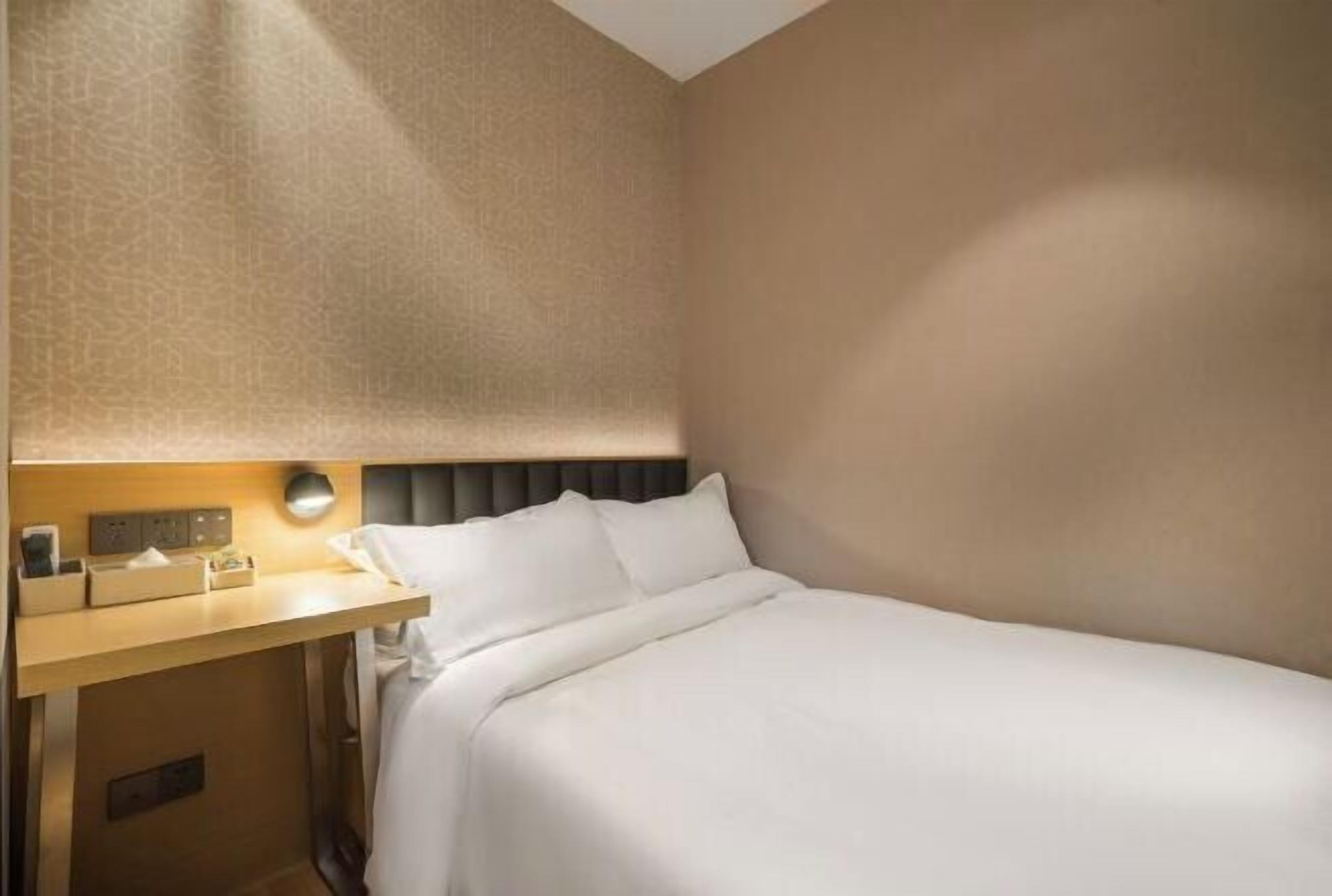 Een hotelkamer met een bed, nachtkastje, lamp en een muur met een reliëfprint.