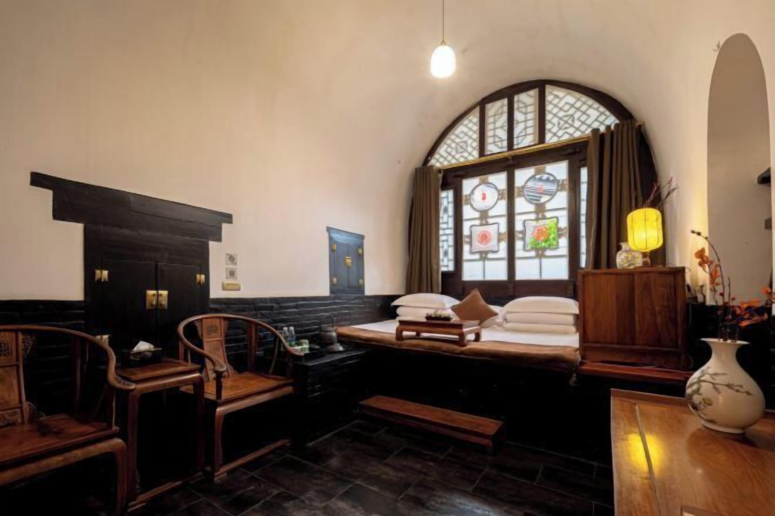 Una camera tradizionale con un letto, mobili in legno, una scrivania e una finestra vista.