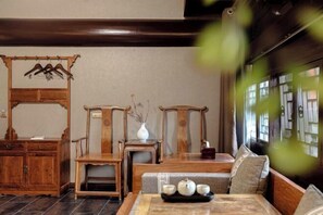 A traditional wooden room with a sofa, a small table with a tray of teaware, and a wooden cabinet. - Jing Xiu Wudedi Cultural Hall (Pingyao County)