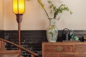 A wooden bench with a vase of flowers and a lamp. - Jing Xiu Wudedi Cultural Hall (Pingyao County)