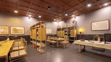 A room with a long wooden table, several chairs, and built-in wooden bookshelves.