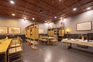 A room with a long wooden table, several chairs, and built-in wooden bookshelves. - Jing Xiu Wudedi Cultural Hall (Pingyao County)