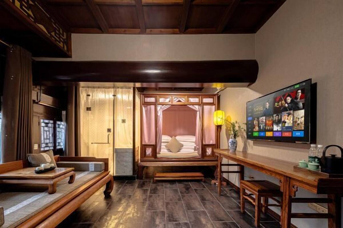 A traditional room with a bed, a wooden bench, a table, and a TV on the wall.