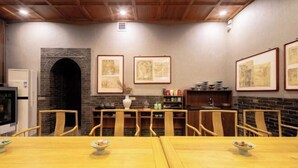 Un comedor con mesas y sillas de madera, una chimenea de ladrillo y obras enmarcadas en las paredes.