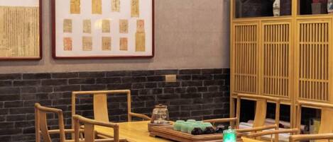 A dining area with a wooden table and chairs, framed documents on the wall, and a wooden cabinet with items on top.