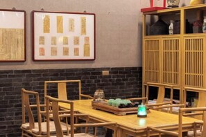 Een eethoek met een houten tafel en stoelen, ingelijste documenten aan de muur en een houten kast met spullen erop.