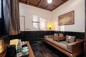A room with a wooden bench, a table with a kettle and water bottles, a wall-mounted light, and a framed plaque. - Jing Xiu Wudedi Cultural Hall (Pingyao County)