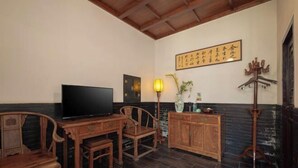 Habitación tradicional con televisor, muebles de madera, lámpara de pared y una pieza decorativa con caligrafía.