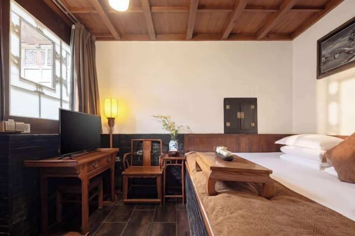 A room with a bed, a desk, a chair, a lamp, and a window.