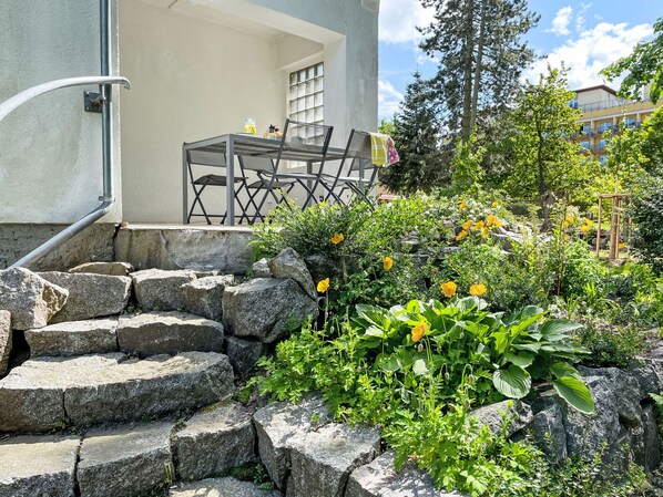 A set of stone steps leading to a building with a white exterior and a window with a grid pattern.