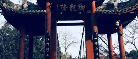 A traditional Chinese gate with inscriptions, leading to a pathway.
