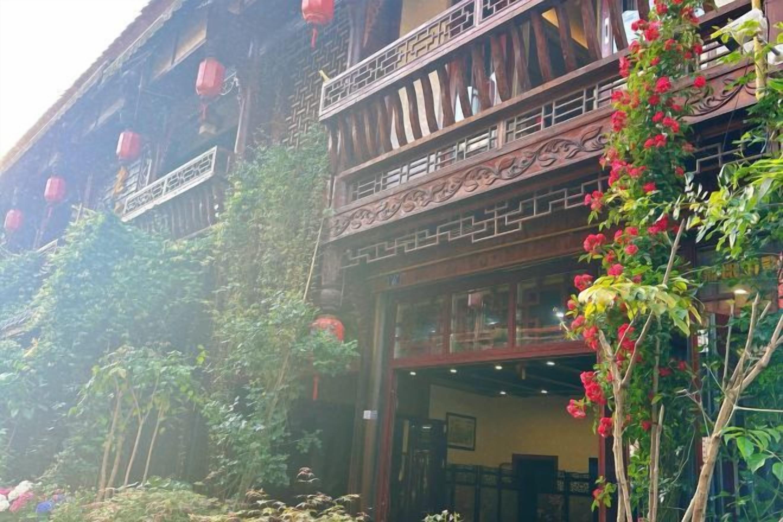 Un edificio tradicional con balcón, asientos exteriores y faroles rojos.