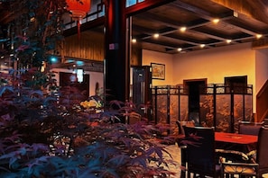 An indoor dining area with a traditional Asian decor, featuring a red table, black chairs, and a decorative screen. - Jiezi Ancient Town Old Manor (Chongzhou)