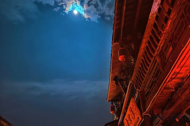 A night sky with a visible moon and clouds.