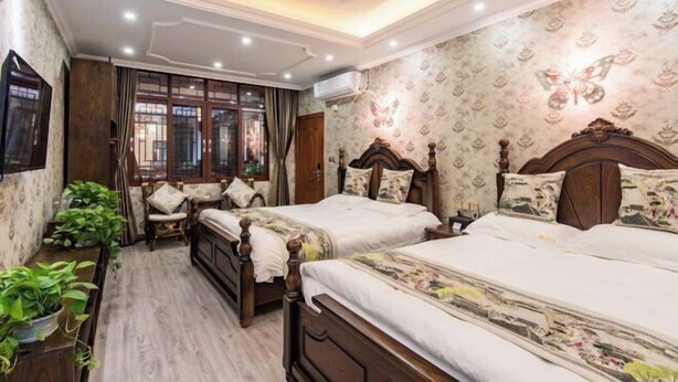 Un dormitorio tradicional con dos camas de madera, una mesita de noche de madera, una ventana con cortinas y un aire acondicionado instalado en la pared.