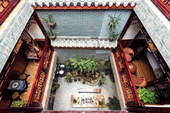 A traditional courtyard with a tiled roof, a stone wall, and various plants and furniture. - Jiezi Ancient Town Old Manor (Chongzhou)