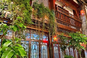 A traditional building with multiple balconies and wooden railings, featuring intricate designs and lush greenery. - Jiezi Ancient Town Old Manor (Chongzhou)