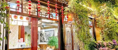 A traditional Chinese courtyard with a wooden gate, red lanterns, and lush greenery.