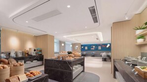 A modern hotel lobby with marble counters, a reception desk, and a blue wall with signage.